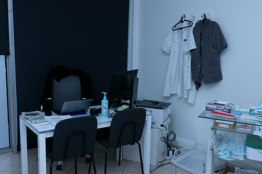 Bureau de consultation avec table, sièges et blouses accrochées au mur