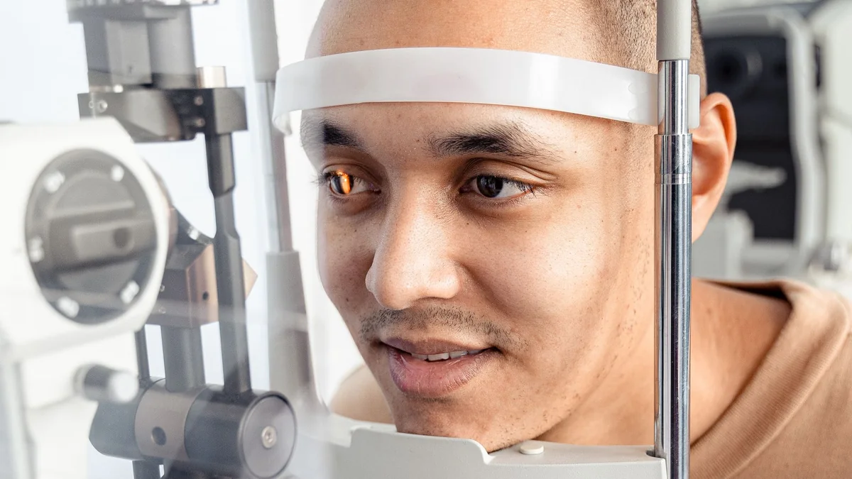 Patient installé devant une lampe à fente, front appuyé sur le bandeau et menton sur la mentonnière, lors d'un examen ophtalmologique